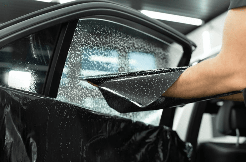Technician applying window film to a vehicle door glass at Tint World Glenview